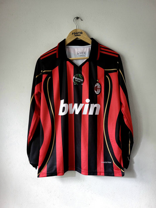 A vintage AC Milan long-sleeve soccer jersey with red and black vertical stripes, gold piping, and a white 'bwin' sponsor logo, hanging on a wooden hanger against a plain wall.