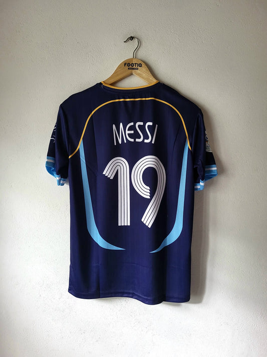 Back view of a dark navy blue soccer jersey with 'MESSI' and the number '19' printed in white, hanging on a wooden hanger against a textured off-white wall.
