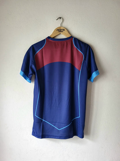 A short-sleeve athletic jersey hanging on a wooden hanger against a plain off-white wall. The back of the shirt is primarily dark blue with a large maroon block across the upper back, light blue piping lines, and light blue sleeve cuffs.