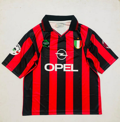 A vintage AC Milan soccer jersey with red and black vertical stripes, featuring the Opel logo, Footprint sponsor, and Italian crest on the chest, laid flat on a light background.