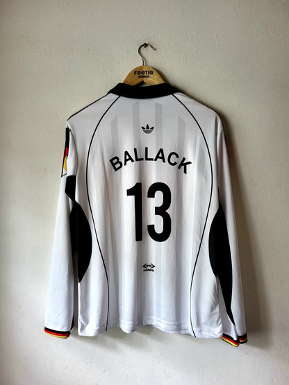 A white long-sleeve Germany national team soccer jersey with 'BALLACK 13' printed on the back, hanging on a wooden hanger against a textured off-white wall.