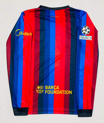 The back of a long-sleeve FC Barcelona soccer jersey with red and navy blue vertical stripes, featuring the Midea sponsor logo on the right shoulder and the UEFA Champions League patch on the left sleeve.