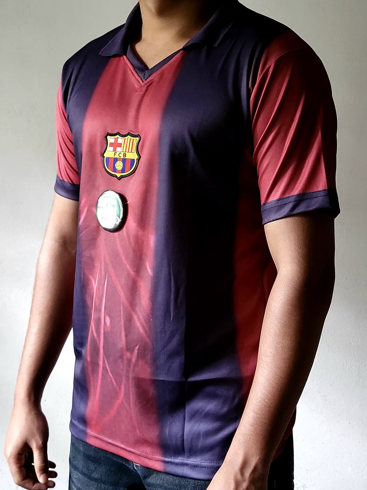 A person wearing a vintage-style FC Barcelona soccer jersey with vertical red and navy stripes, featuring the club crest on the chest and a round badge patch.