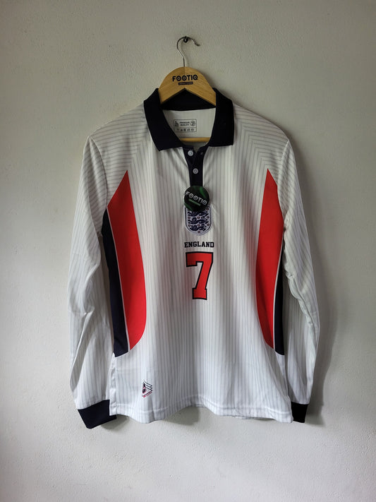 A white long-sleeve England soccer jersey with red and navy blue side panels, hanging on a wooden hanger against a plain wall. The jersey features the number 7 on the front, the England crest, and 'ENGLAND' printed below it.