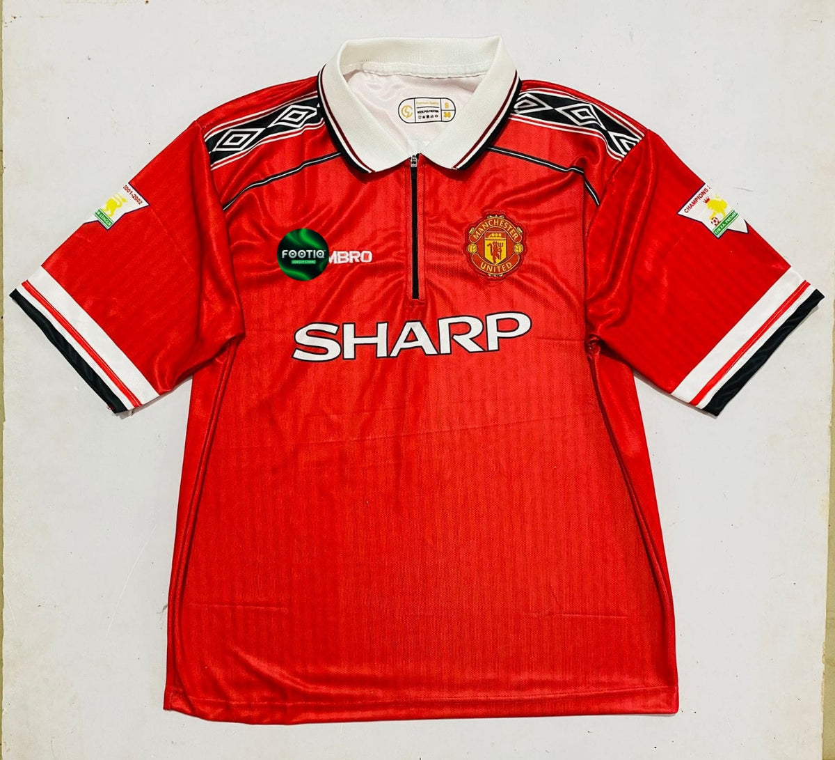A vintage red Manchester United short-sleeve soccer jersey by Umbro, featuring the white 'SHARP' sponsor logo across the chest, the Manchester United crest, and a white collar, laid flat against a light background.