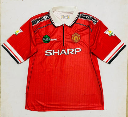 A vintage red Manchester United short-sleeve soccer jersey by Umbro, featuring the white 'SHARP' sponsor logo across the chest, the Manchester United crest, and a white collar, laid flat against a light background.