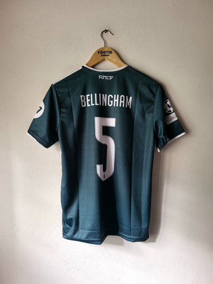 A dark teal FC Copenhagen soccer jersey with 'BELLINGHAM' and the number '5' on the back, hanging on a wooden hanger against a plain wall.
