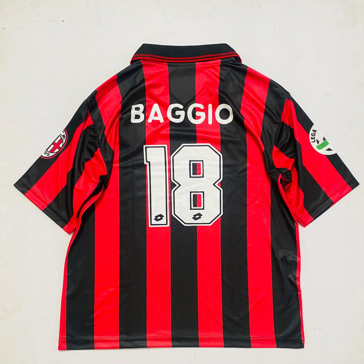 Black and red striped sports jersey with 'BAGGIO' and number '18' on a light gray background