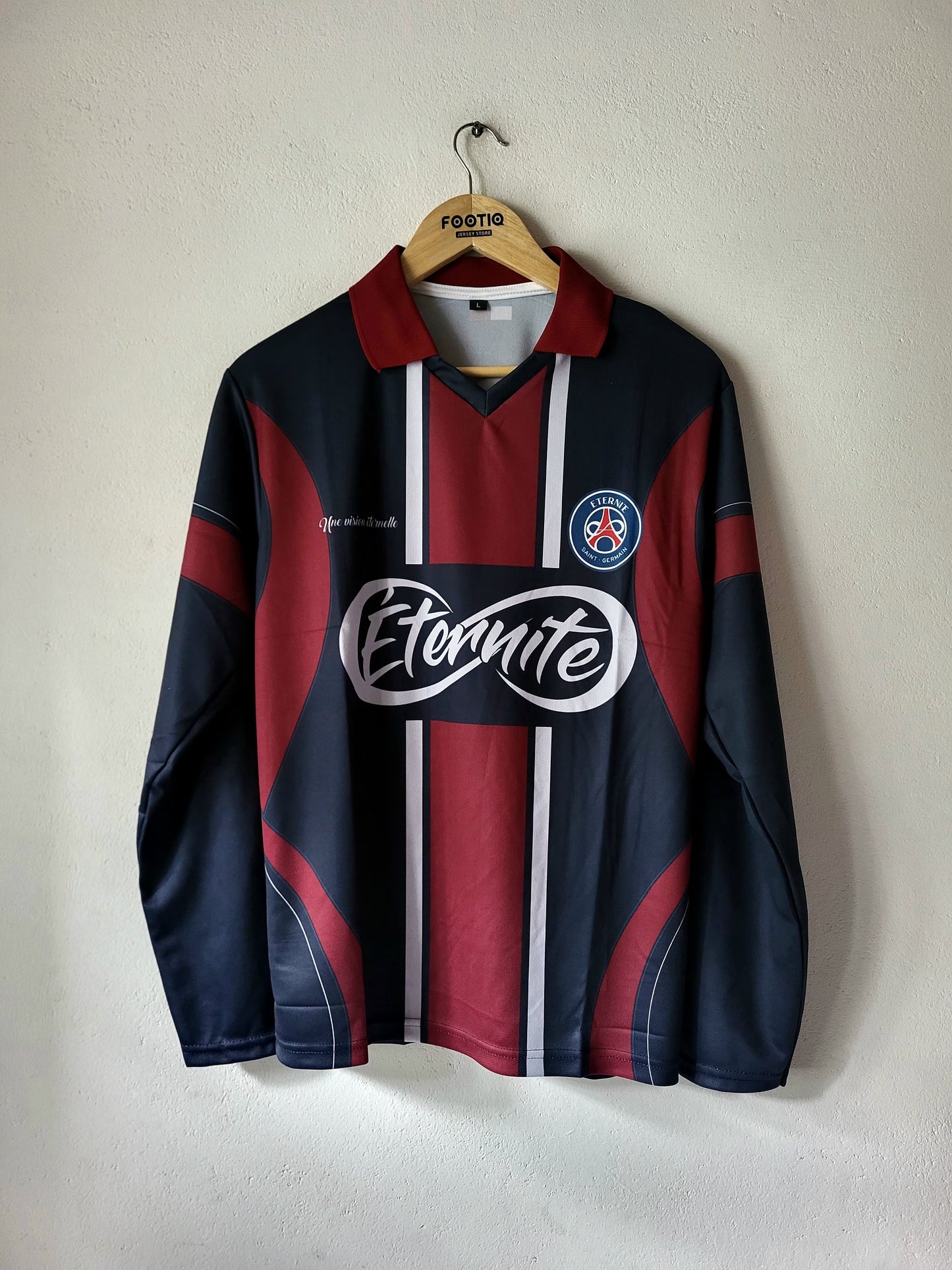 A vintage FC Barcelona long-sleeve soccer jersey in navy blue and maroon, featuring white vertical stripes down the center, a large white 'Etnaite' sponsor logo across the chest, and the club's crest on the left chest. The jersey is hanging on a wooden hanger with 'Festa' printed on it, against a plain off-white wall.