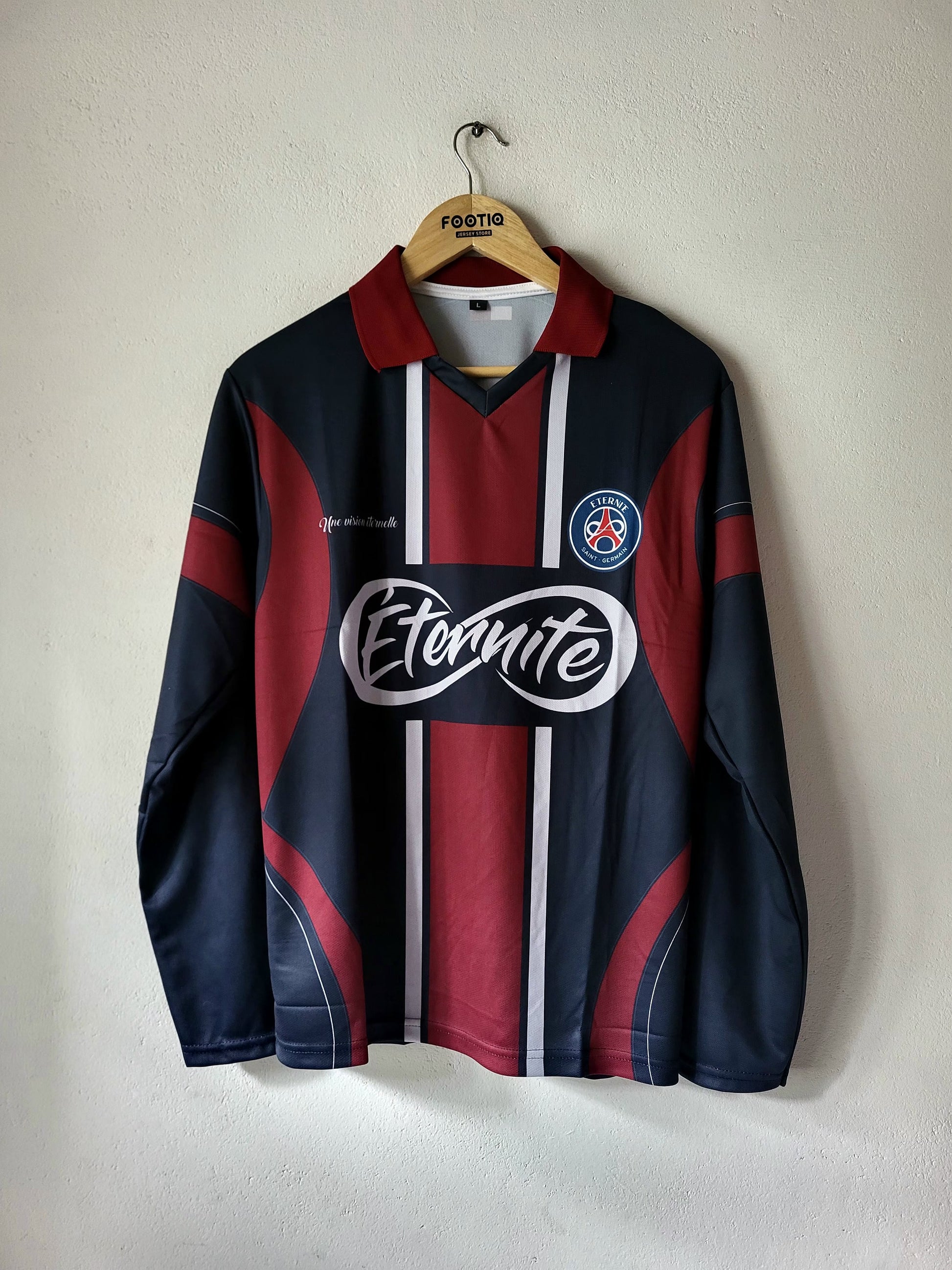 A vintage FC Barcelona long-sleeve soccer jersey in navy blue and maroon, featuring white vertical stripes down the center, a large white 'Etnaite' sponsor logo across the chest, and the club's crest on the left chest. The jersey is hanging on a wooden hanger with 'Festa' printed on it, against a plain off-white wall.