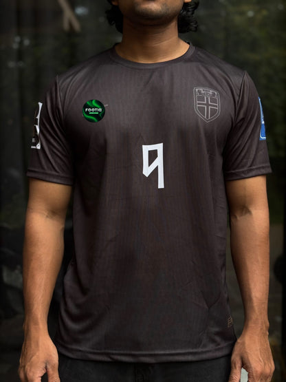 A man wearing a dark gray athletic t-shirt with a white number 9 on the front, a shield crest on the right chest, and a green circular logo on the left chest.