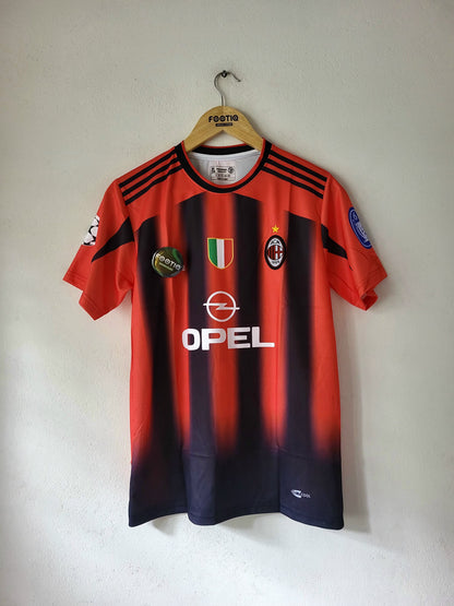 A red and navy striped AC Milan soccer jersey hanging on a wooden hanger against a plain wall. The jersey features the OPEL sponsor logo on the front, the AC Milan club crest, and the Adidas logo on the collar.