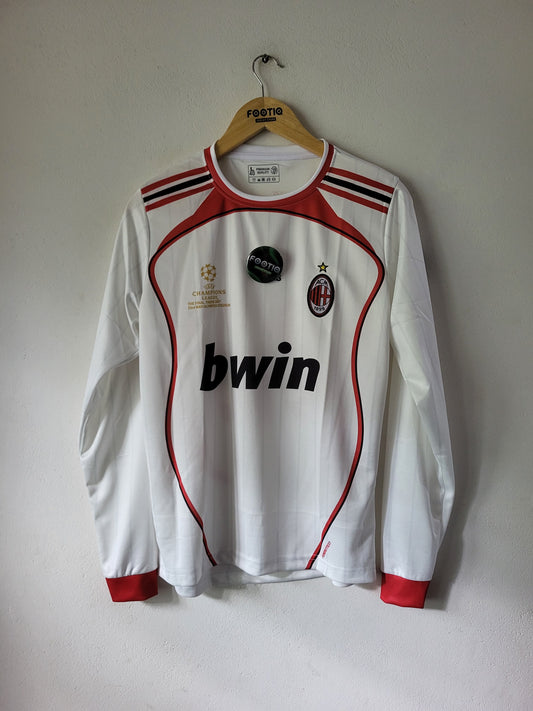 A white long-sleeve AC Milan soccer jersey with red and black trim, hanging on a wooden hanger against a plain light gray wall. The jersey features the 'bwin' sponsor logo on the front, the AC Milan club crest, and UEFA Champions League patches.