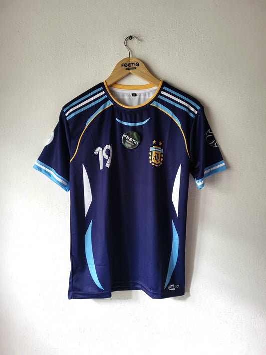 A dark blue Argentina national football team home jersey with light blue and white accents, hanging on a wooden Festio hanger against a plain white wall.