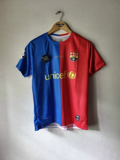 A FC Barcelona soccer jersey hanging on a wooden hanger against a plain light gray wall. The jersey is split vertically into blue on the left and red on the right, with the yellow UNICEF logo across the center, the FC Barcelona crest on the left chest, and a black sponsor patch on the right chest.