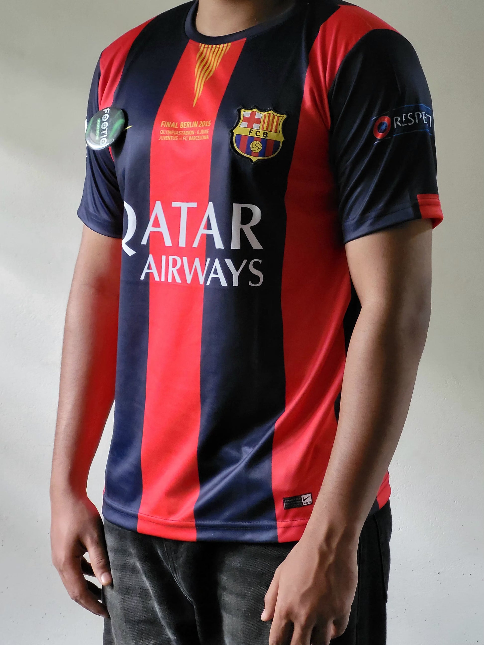 A person wearing a FC Barcelona home soccer jersey with red and navy blue vertical stripes, featuring the club crest and Qatar Airways sponsor logo.