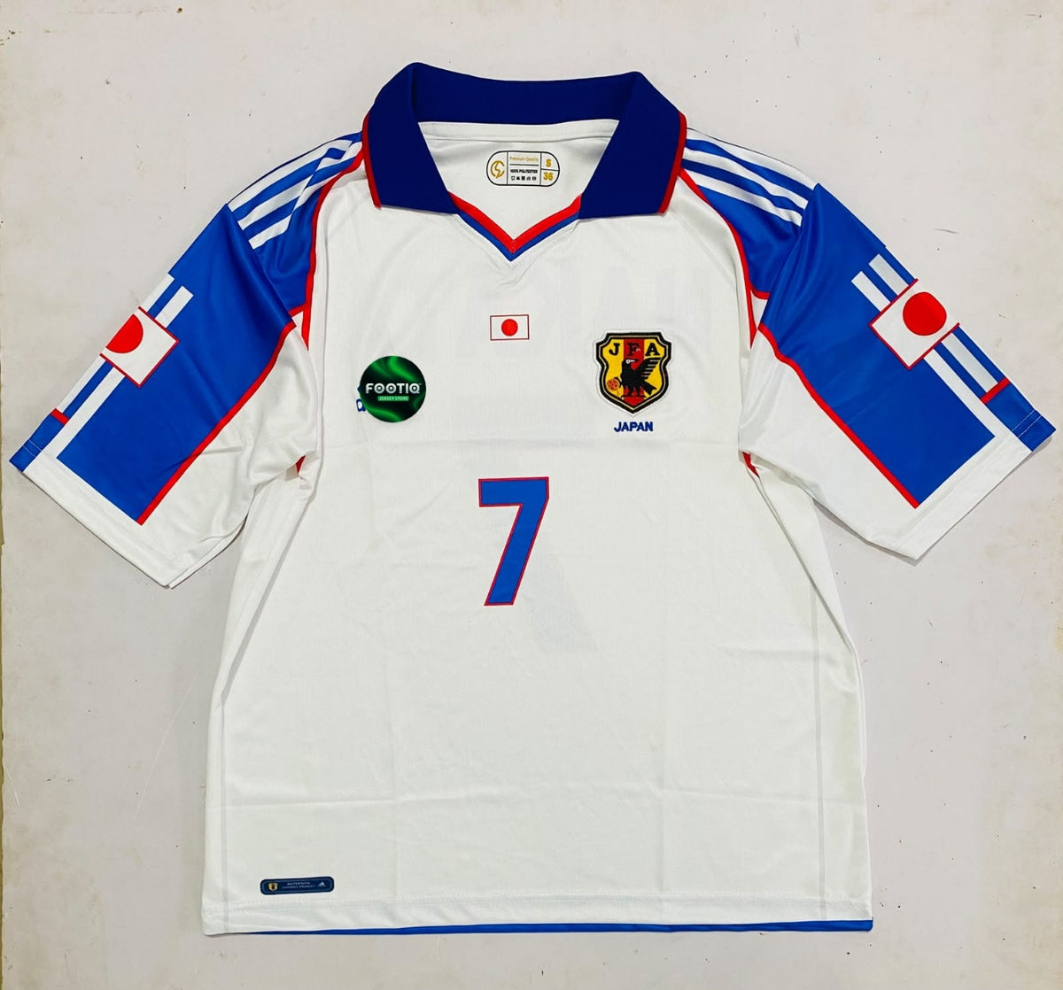A vintage white Japan national football team jersey with blue and red accents, featuring the number 7 on the front, a Japanese crest, and sponsor logos including Yomi and Proton.