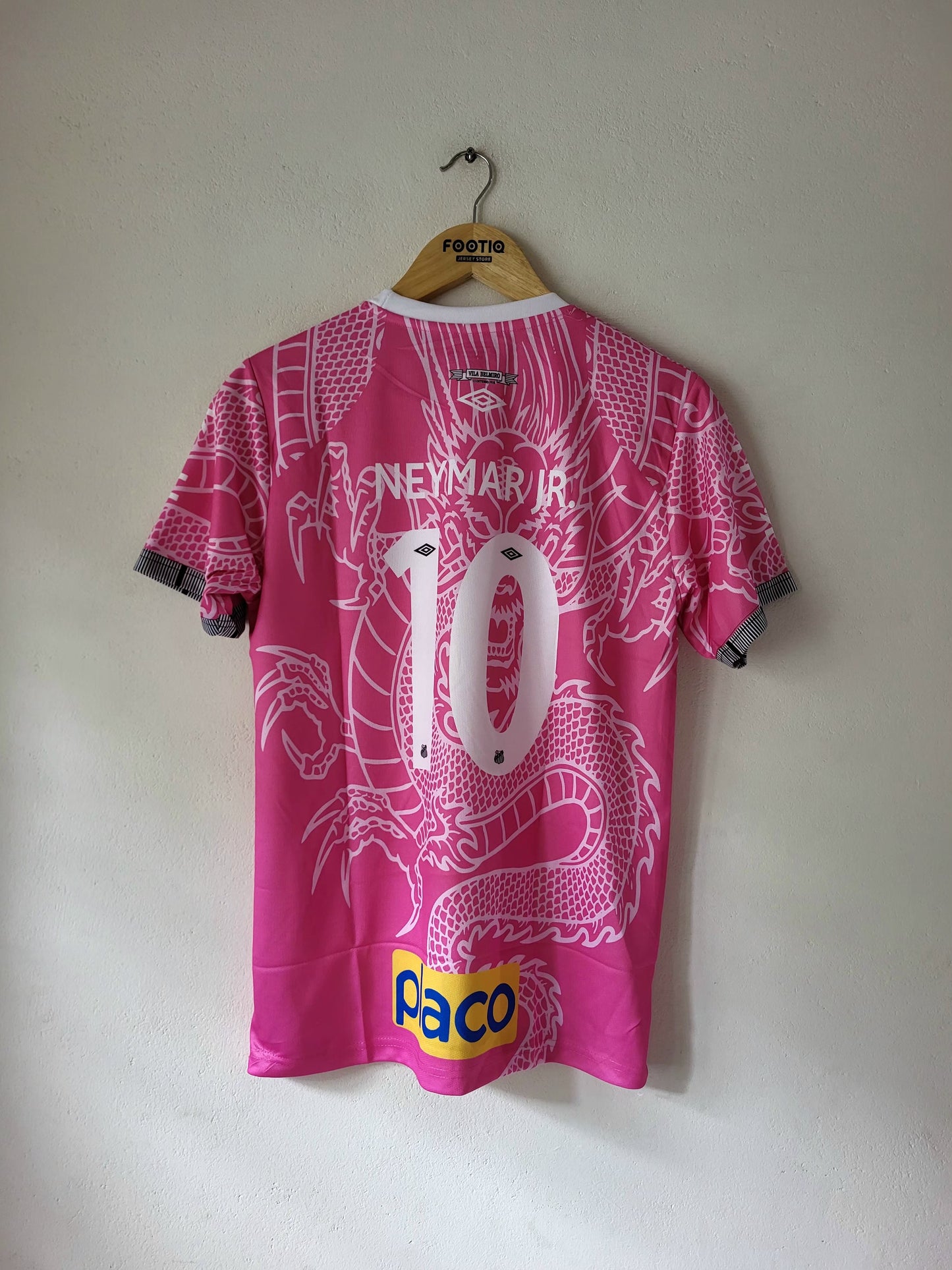 Pink Neymar Jr. number 10 soccer jersey with a white dragon graphic, hanging on a wooden hanger against a plain wall.