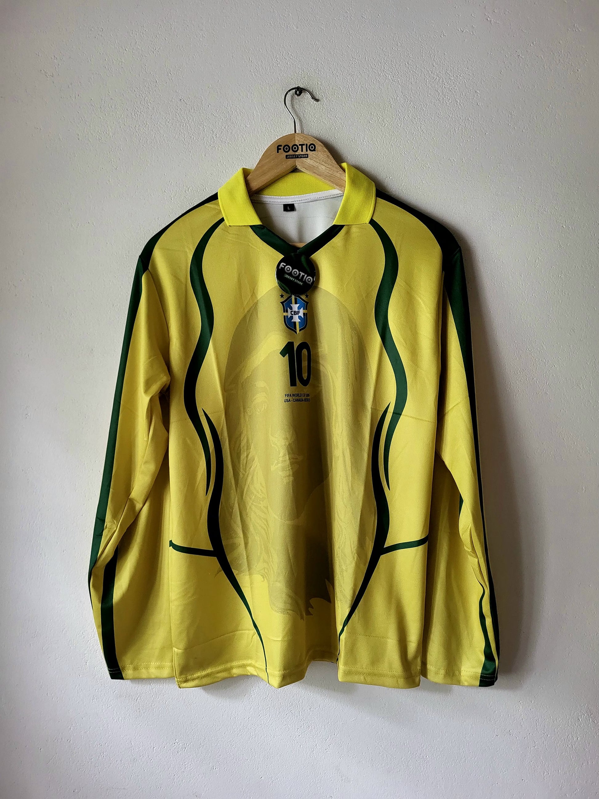 A vintage yellow Brazil national team long-sleeve soccer jersey with green stripes and the number 10, hanging on a wooden hanger against a plain wall.