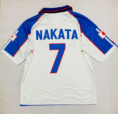 Back view of a white soccer jersey with blue and red trim, featuring the name 'NAKATA' and number '7' in blue with red outlines on the back.