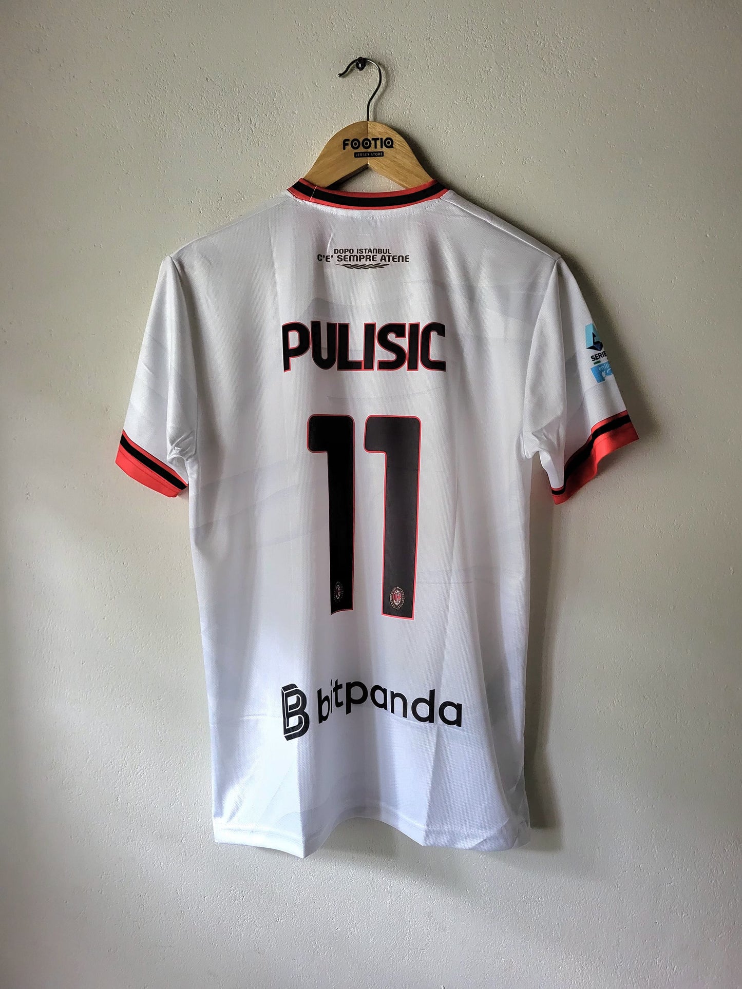 A white FC Copenhagen football jersey with 'PULISIC 11' printed on the back, hanging on a wooden hanger against a plain wall.