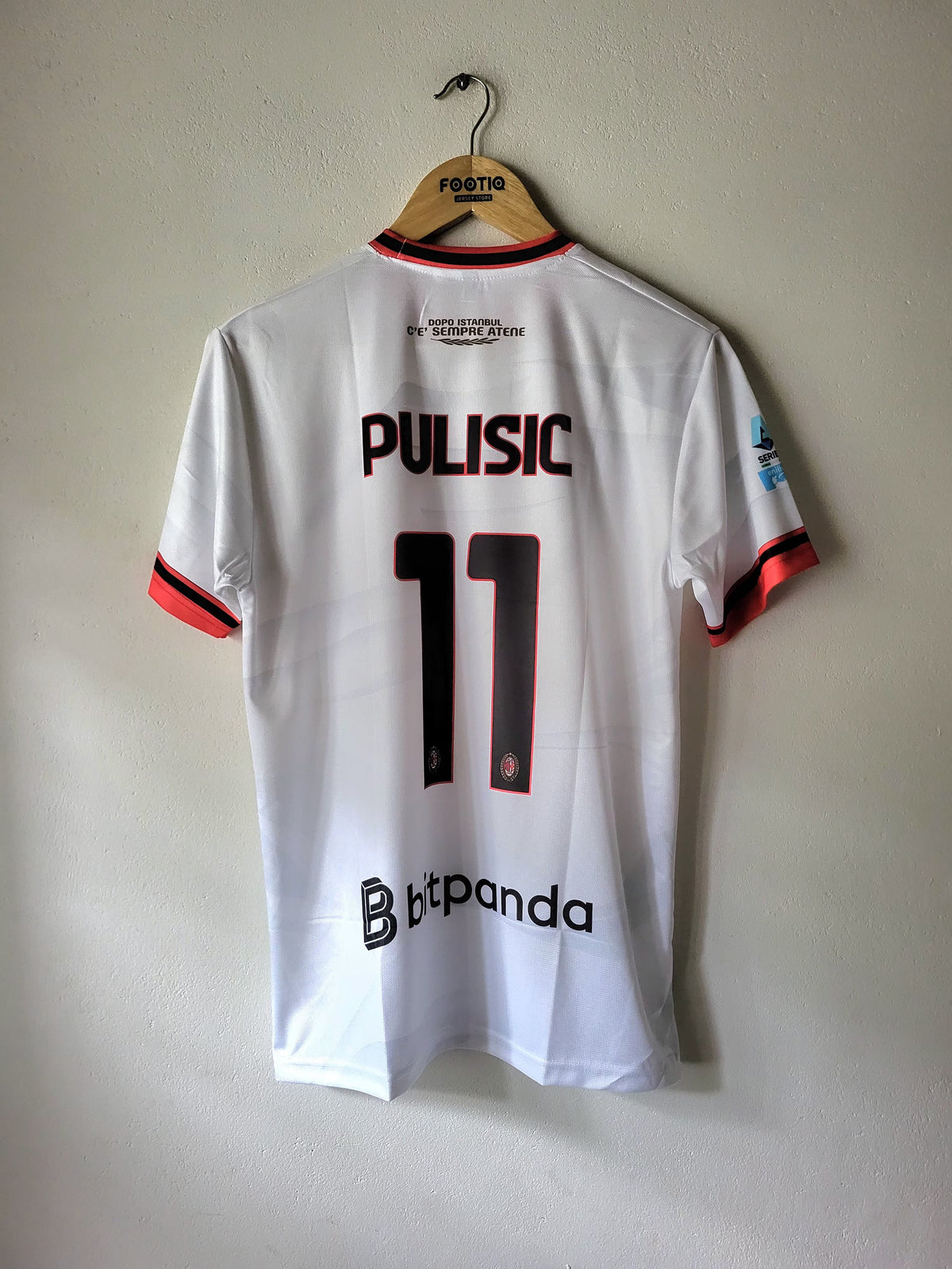 A white FC Copenhagen football jersey with 'PULISIC 11' printed on the back, hanging on a wooden hanger against a plain wall.