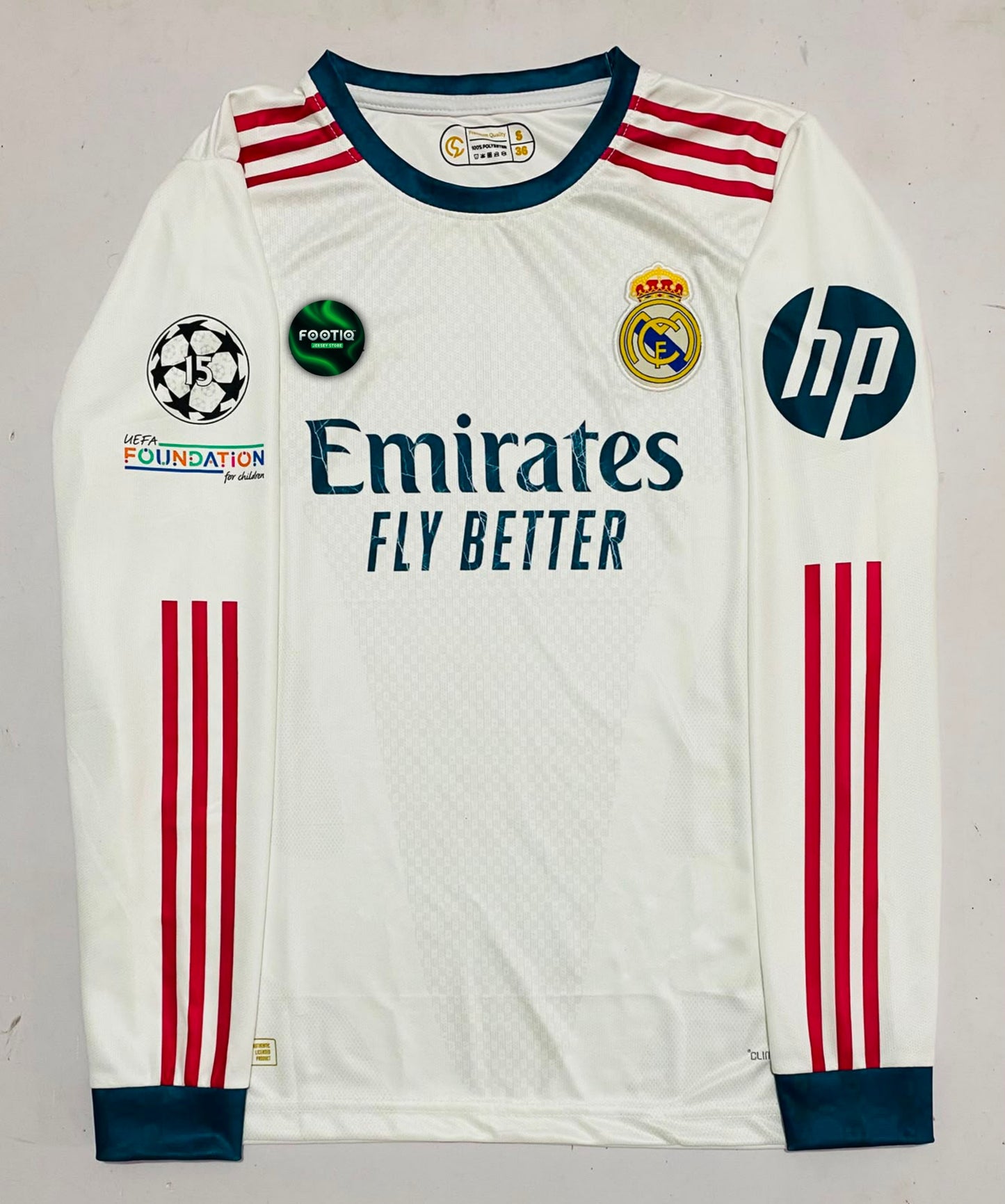 A white Real Madrid long-sleeve soccer jersey with red and navy details, featuring the Emirates Fly Better sponsor logo, Adidas three-stripes, and HP logo on the sleeve.