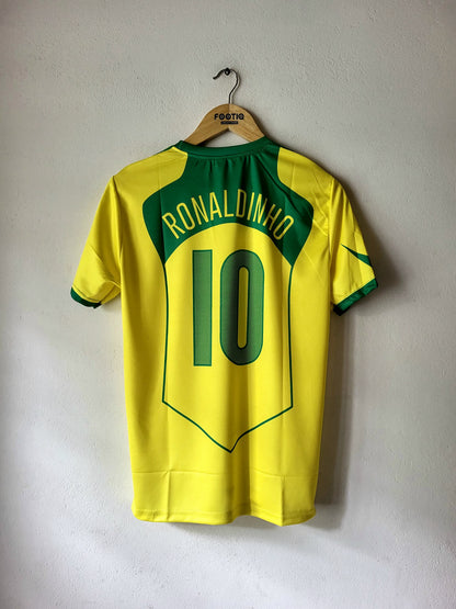 A yellow and green Brazil soccer jersey with 'RONALDINHO' and the number '10' printed on the back, hanging on a wooden hanger against a light gray wall.