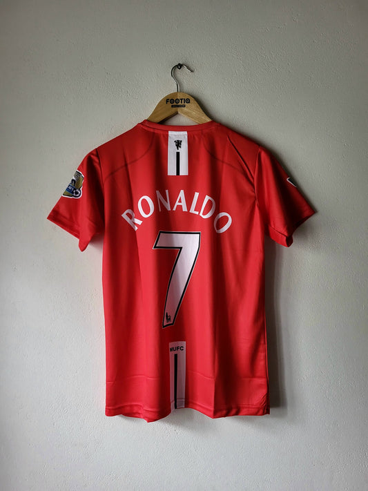 A red short-sleeve soccer jersey hanging on a wooden hanger against a light gray wall. The back of the jersey shows 'RONALDO' and the number '7' in white with black outlines, and a Premier League patch is visible on the left sleeve.