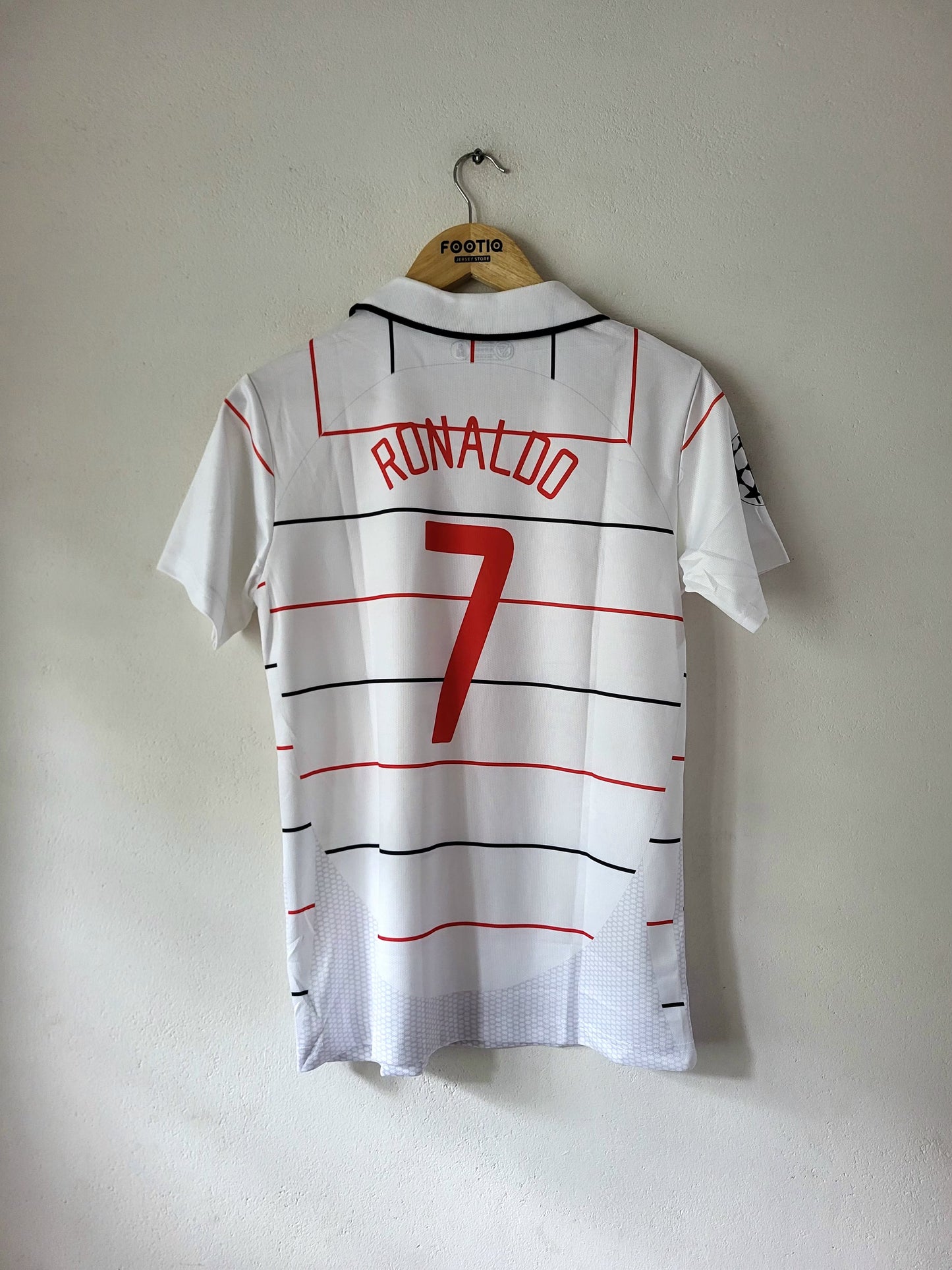 A white Portugal soccer jersey with 'RONALDO 7' printed on the back, hanging on a wooden hanger against a plain wall.