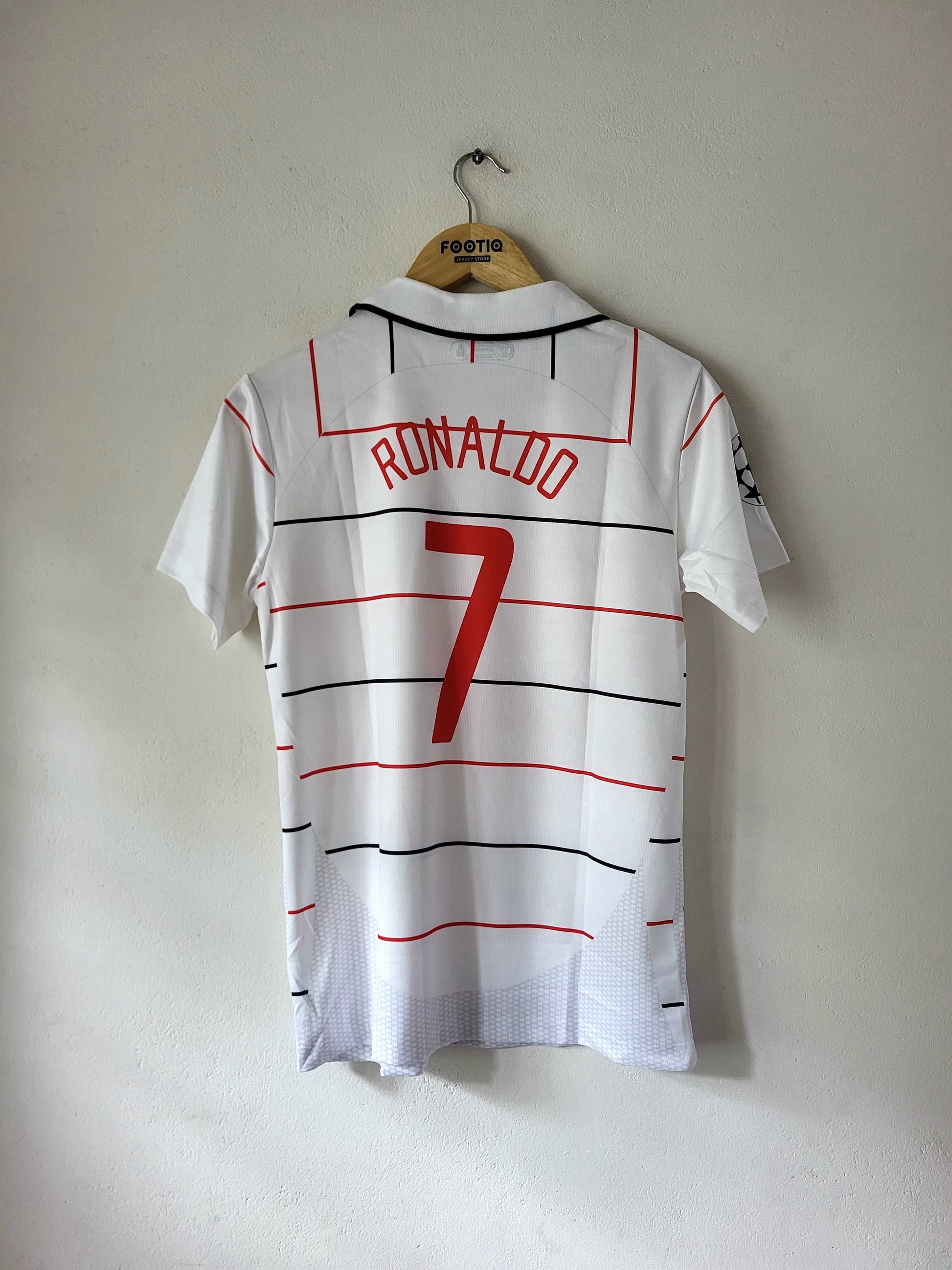A white Portugal soccer jersey with 'RONALDO 7' printed on the back, hanging on a wooden hanger against a plain wall.