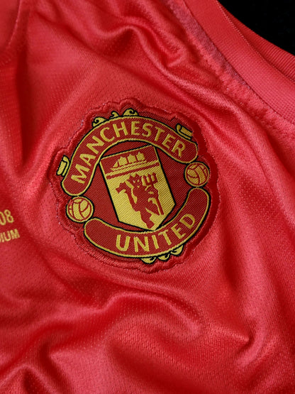 Close-up of a red Manchester United soccer jersey fabric with the embroidered club crest in gold and red.