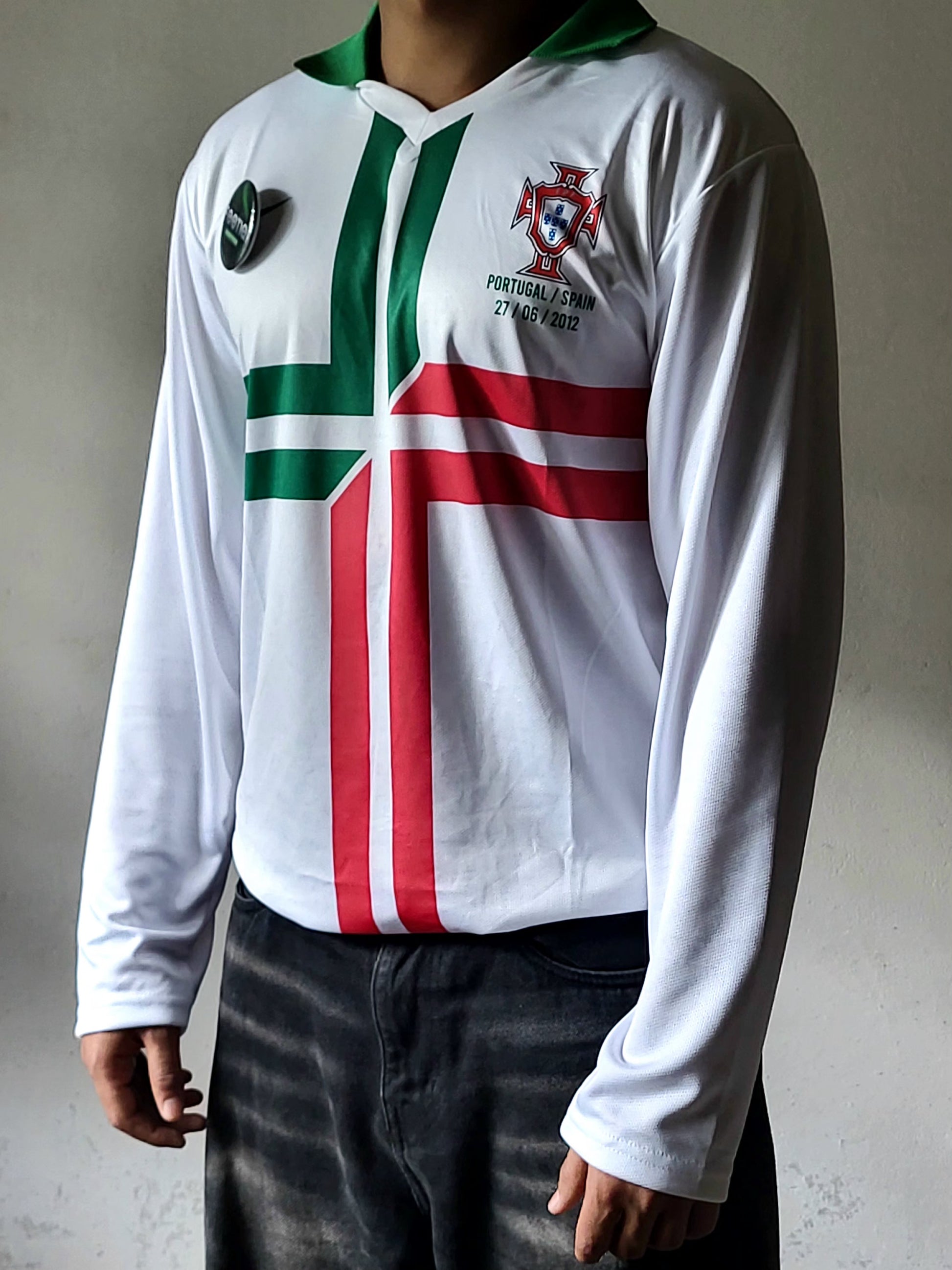 A long-sleeve white Portugal football jersey with green and red vertical and horizontal cross motifs, worn by a model against a neutral gray wall.