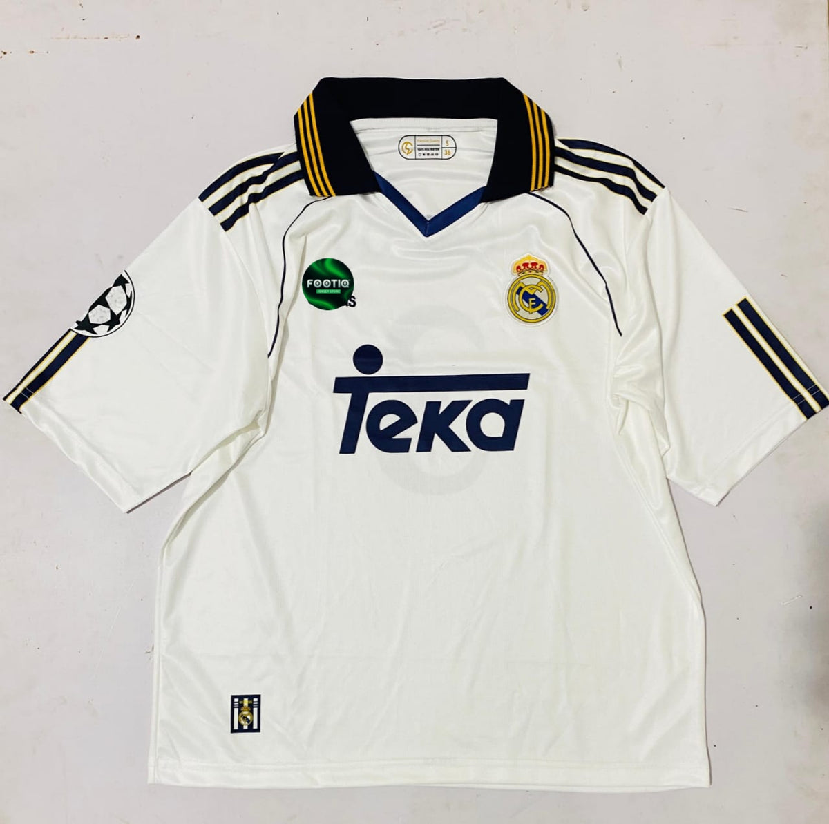 A vintage Real Madrid home soccer jersey from the 2004-2005 season, featuring a white body with a navy blue V-neck collar, navy blue shoulder stripes, and the 'Teka' sponsor logo on the chest.