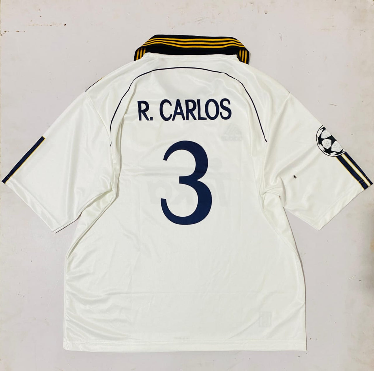 White sports jersey with 'R. Carlos' and number '3' on a light gray background