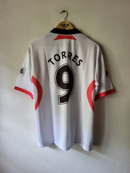 White short-sleeve soccer jersey hanging on a wooden hanger against a plain wall, with the back showing 'TORRES' and the number 9 in black, plus red side accents.
