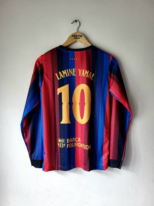 A long-sleeve FC Barcelona football jersey with the back of the number 10 'Lamine Yamal' printed in gold, hanging on a wooden hanger against a white wall.