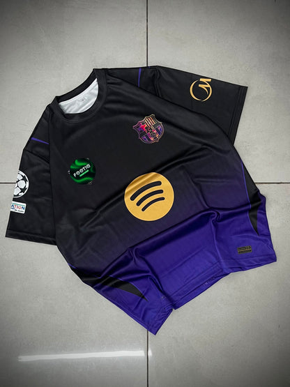 A black and purple gradient FC Barcelona soccer jersey with a yellow Spotify sponsor logo, laid flat on a gray tiled floor.