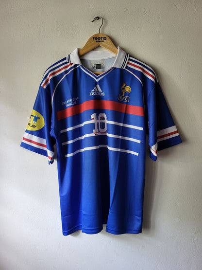 A blue France national football team Adidas jersey with red and white stripes, hanging on a wooden hanger against a plain wall. The jersey features the number 10 on the front, the Adidas logo, and the FIFA crest.