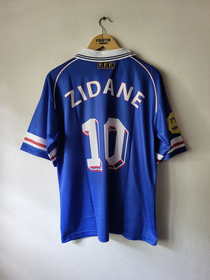 A blue France national football team jersey with 'ZIDANE' and the number '10' on the back, hanging on a wooden hanger against a plain wall.
