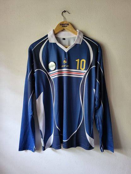 A blue long-sleeve France national football team jersey with white and red graphic details, hanging on a wooden hanger against a plain wall. The jersey features the number 10 on the right chest and the FFF crest on the left.
