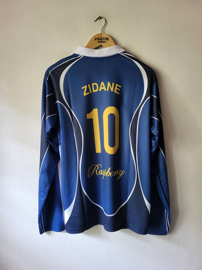 A blue long-sleeve soccer jersey hanging on a wooden hanger against a plain wall. The back of the shirt features 'ZIDANE' and the number '10' in yellow, with 'Raspberry' in yellow script below.