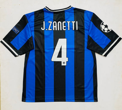 Back view of an Inter Milan soccer jersey with blue and black vertical stripes, featuring the name 'J.ZANETTI' and number '4' in white on the back, with a UEFA Champions League patch on the sleeve.